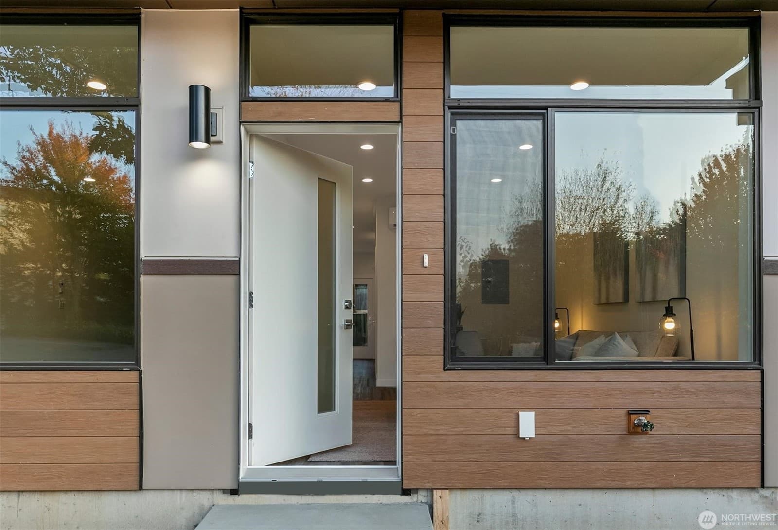 Entry with the door open, wood siding and full-height glass alongside