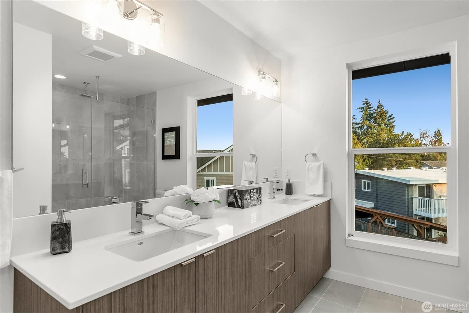 Bathroom vanity with a window over the counter and the glass shower beyond