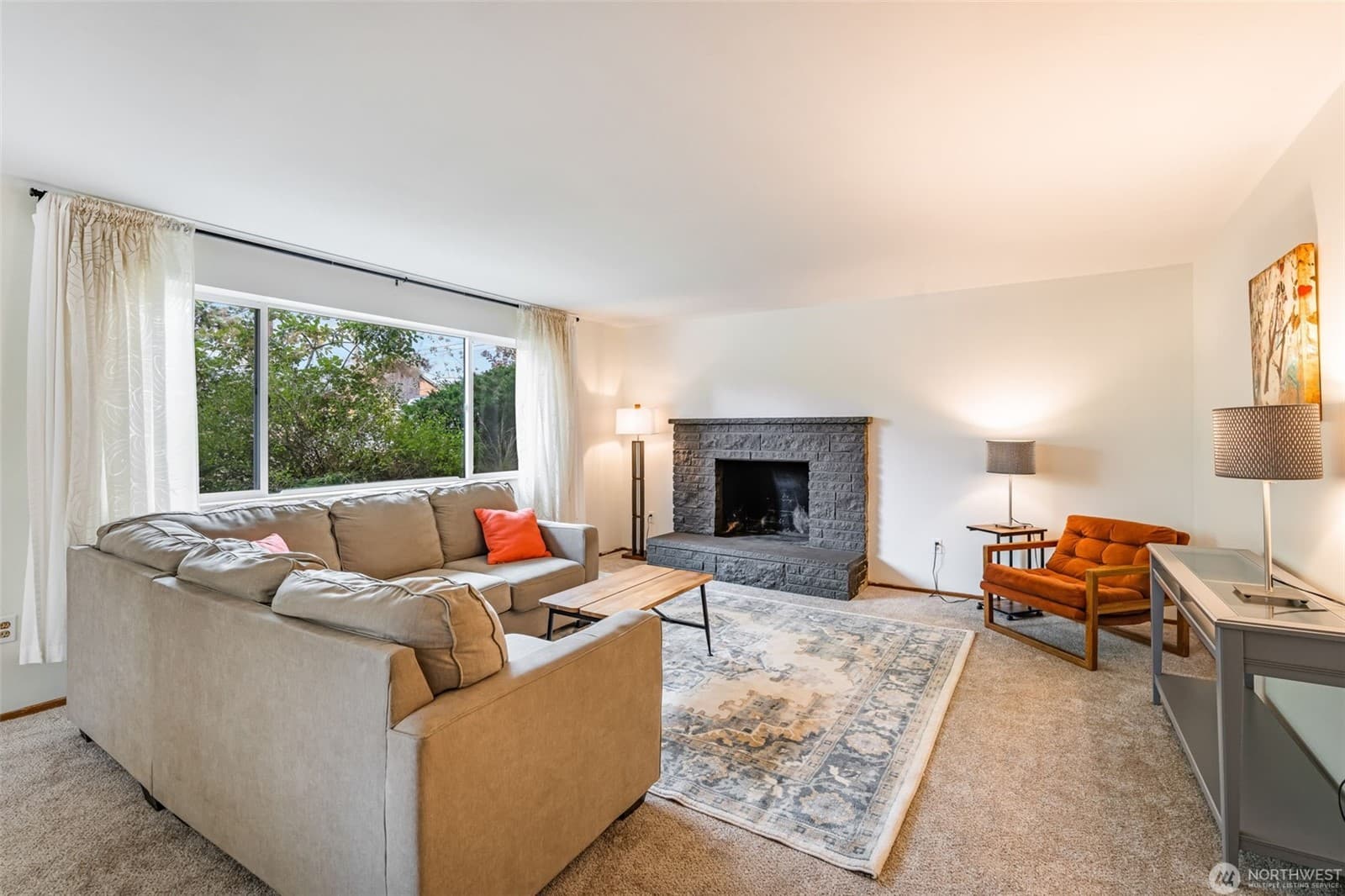 Living room with a stone fireplace and a wide picture window