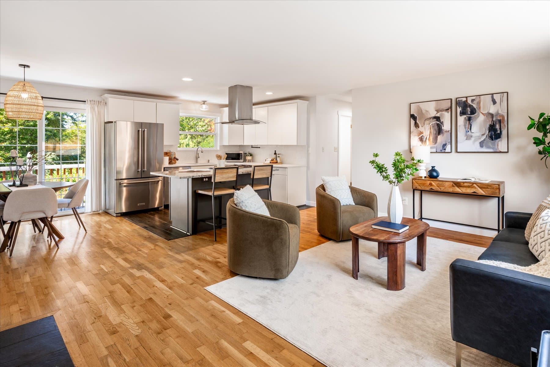 Open living and kitchen area on oak floors, looking toward the island and range hood