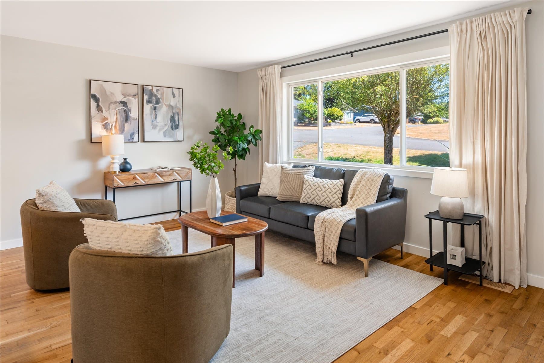 Living room with a wide picture window over the front yard and oak floors
