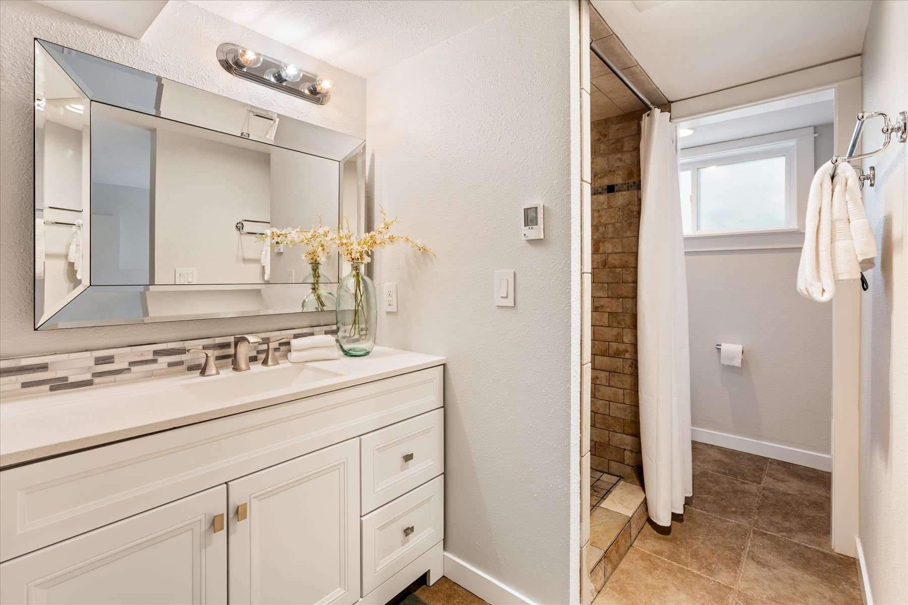 Second updated bathroom with a walk-in shower and white vanity