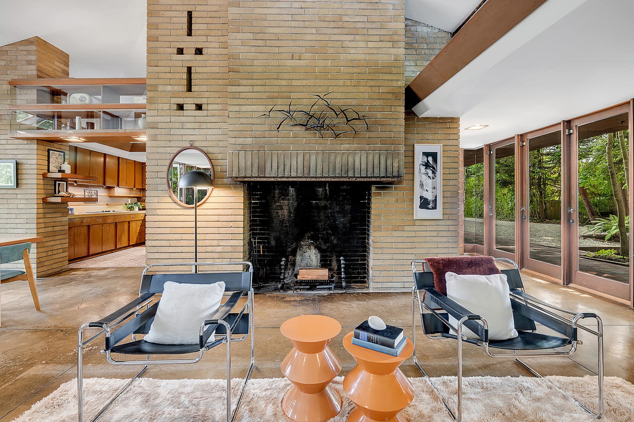 Brick fireplace flanked by built-in shelving and a round mirror