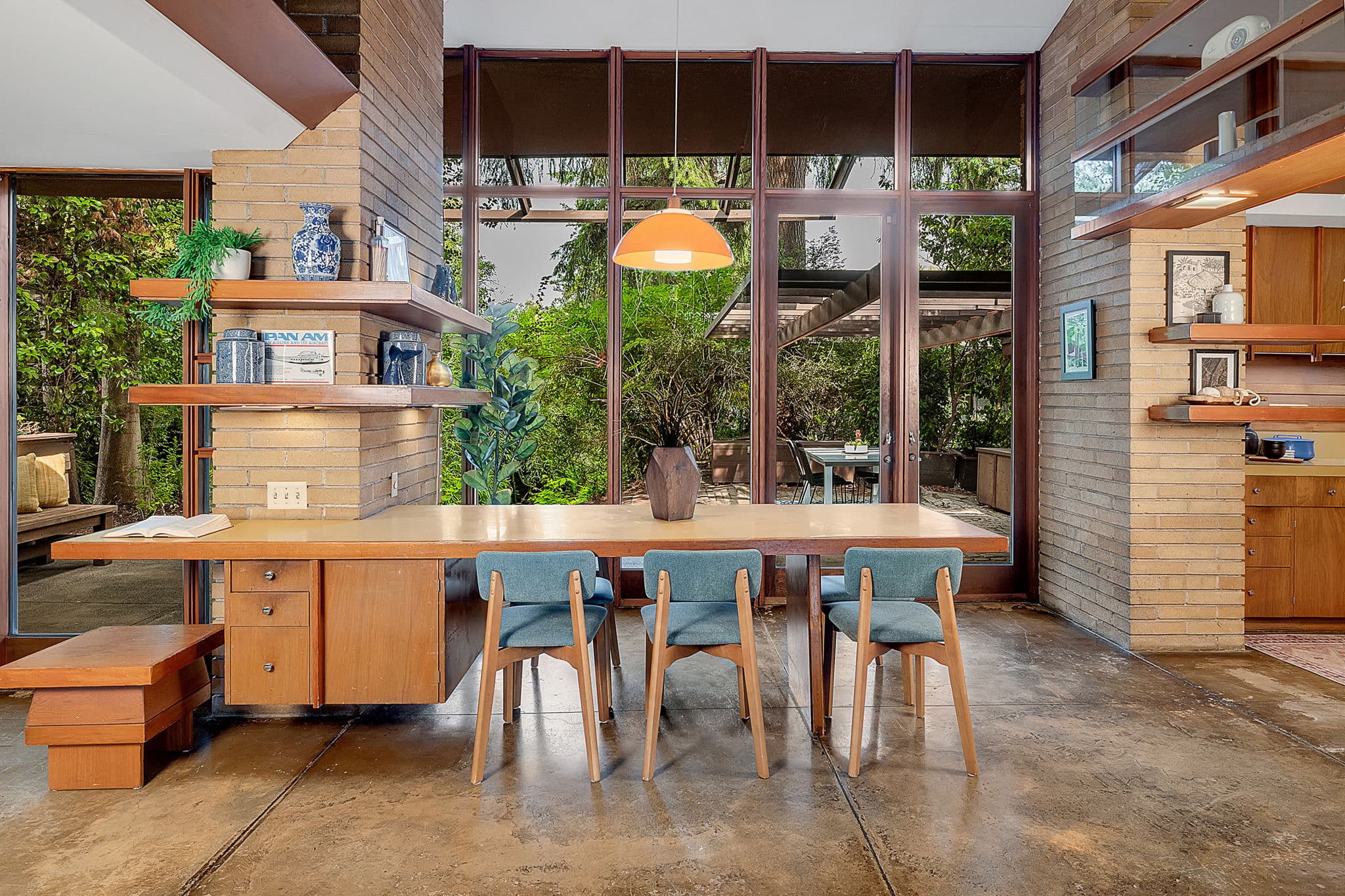 Dining area beside a brick column, with built-in shelving beyond