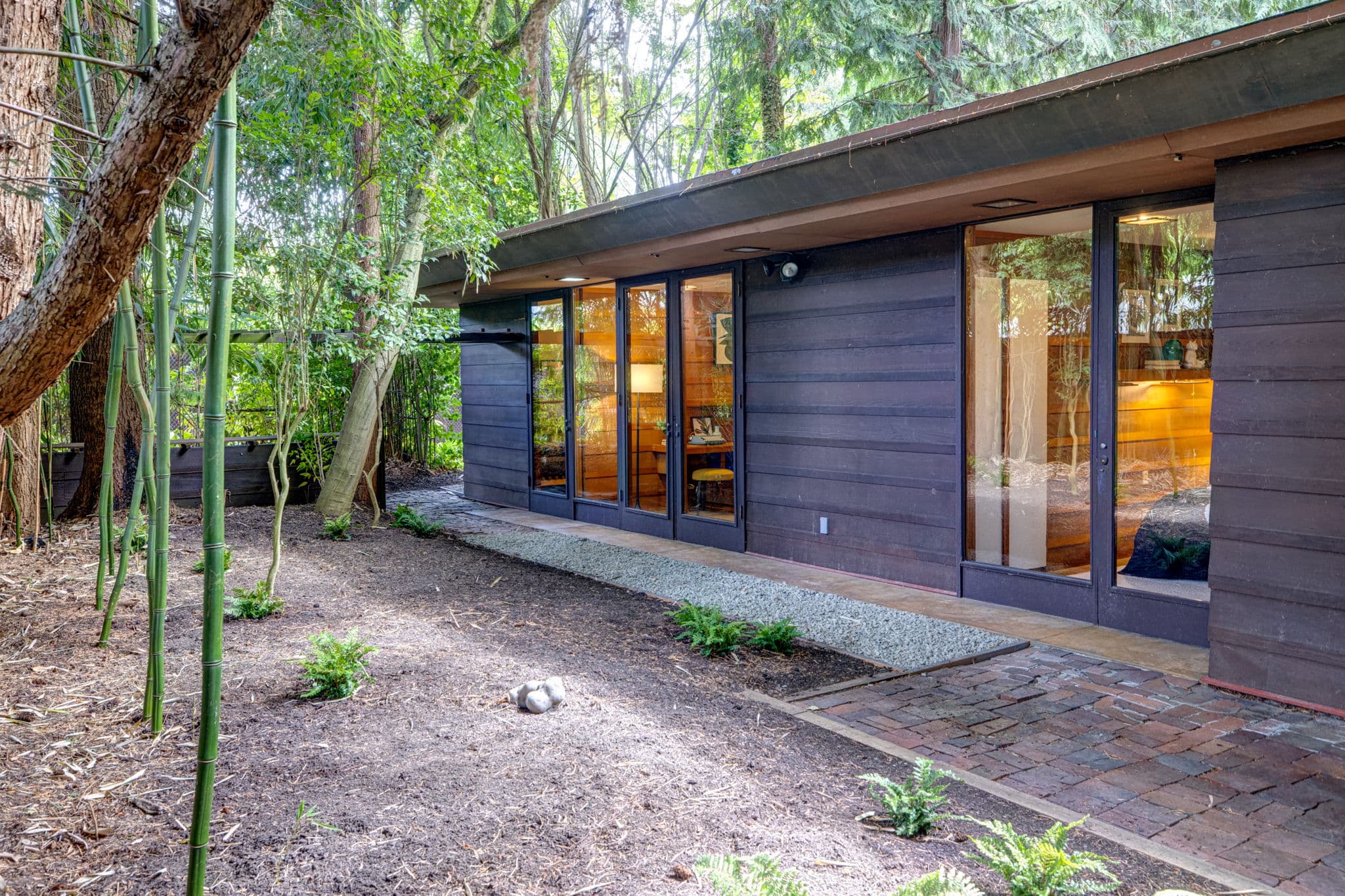 The house seen through the trees, its windows lit