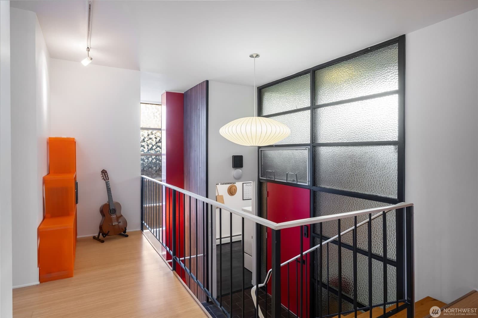 The landing from the opposite side, looking through the gridded glass wall to the stair