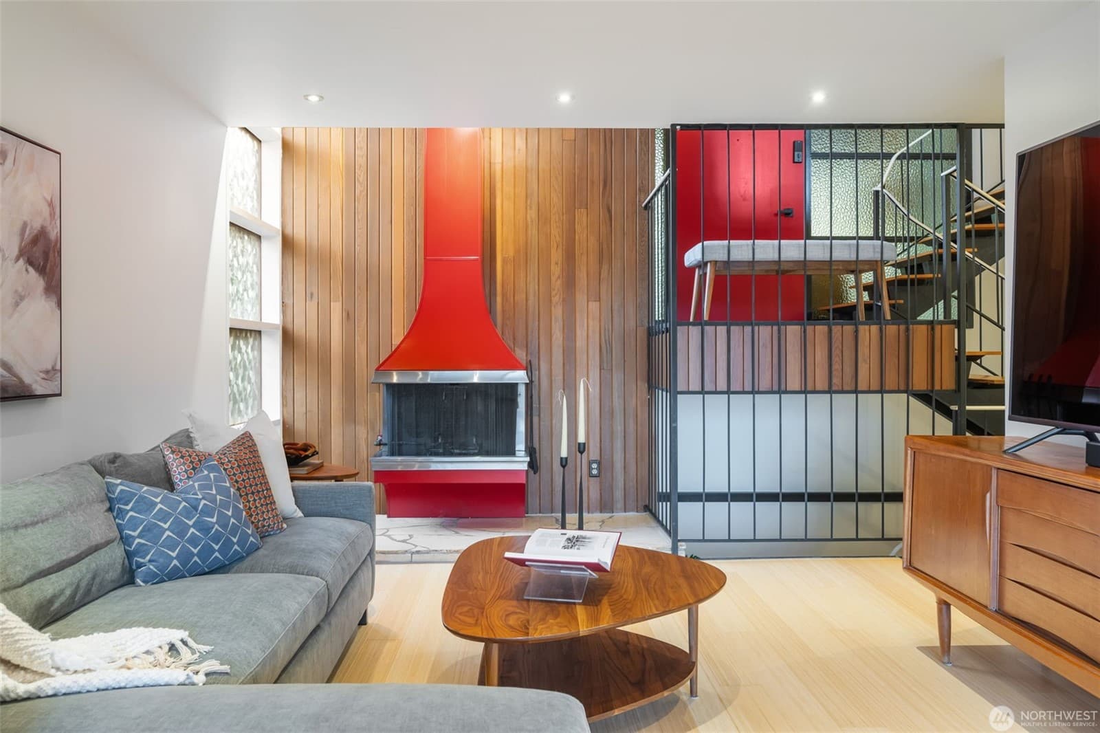 Living room anchored by the red sculptural fireplace, with a gridded screen dividing the space