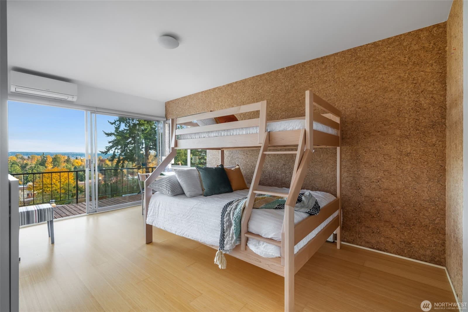 Bedroom with bunk beds against a textured feature wall and glass onto the deck