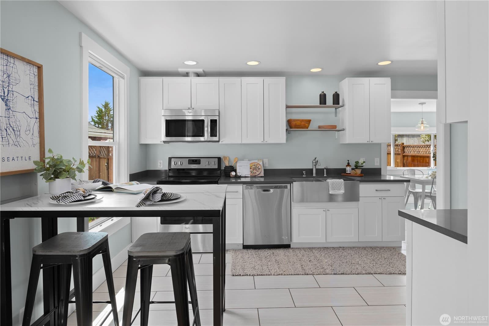 Kitchen with white cabinets, dark counters, stainless appliances and bar seating