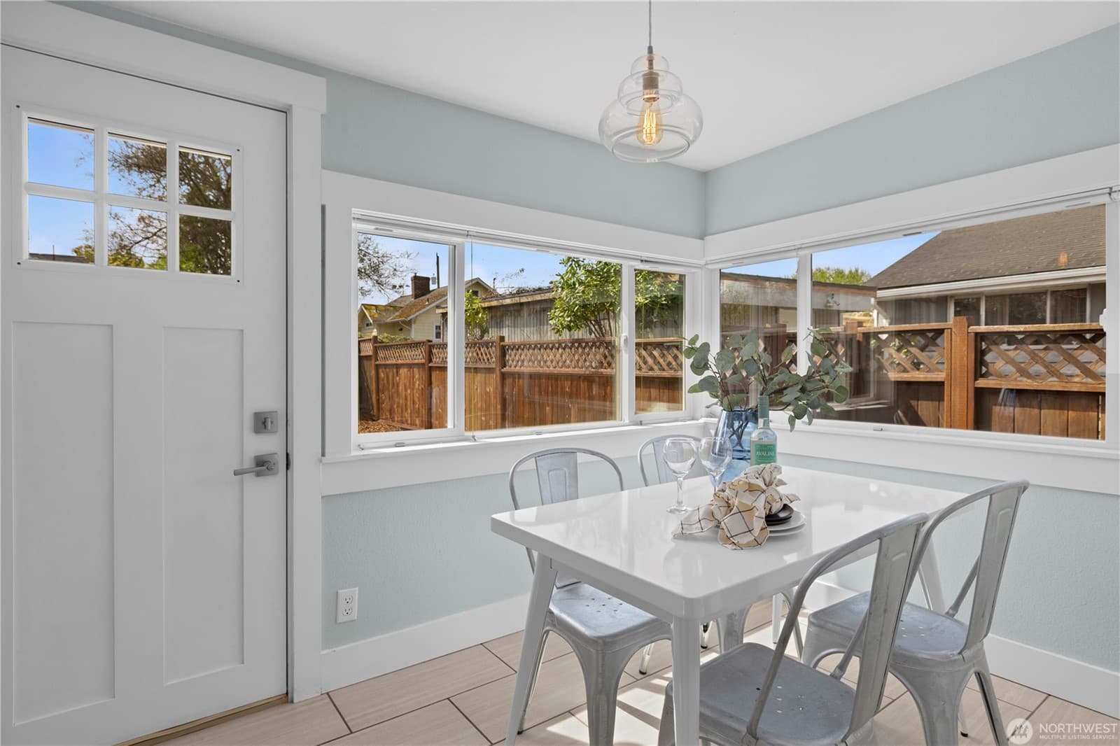 Breakfast nook with windows on two sides and a door out to the fenced yard