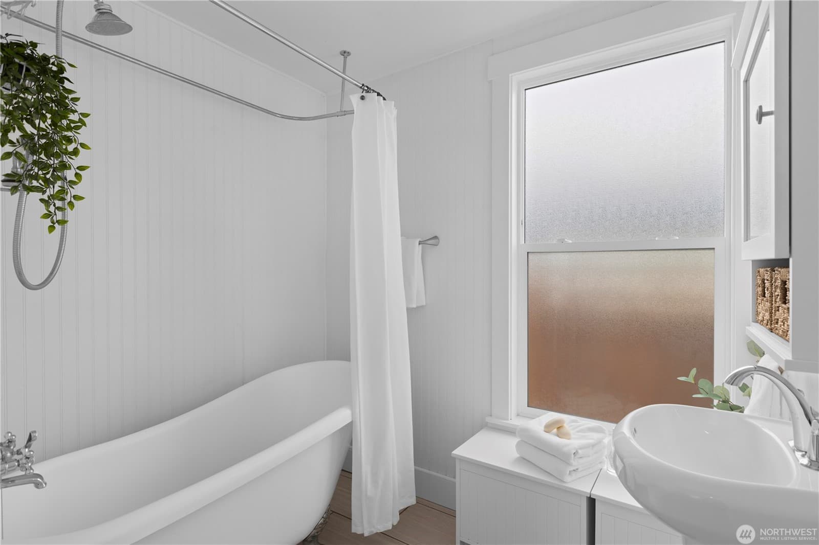 Bathroom with a soaking tub and shower, pedestal sink and frosted window